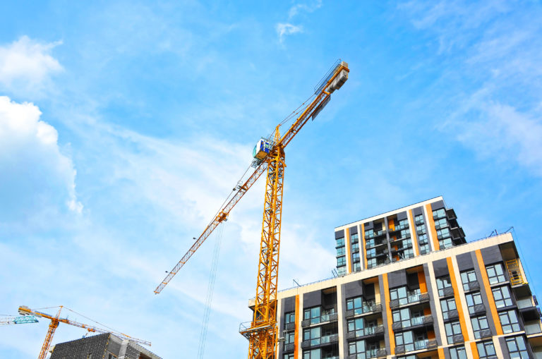 Crane and building under construction against blue sky