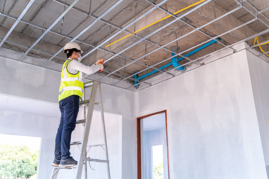 commercial renovation costs: a construction worker working on a ladder inside a commercial building
