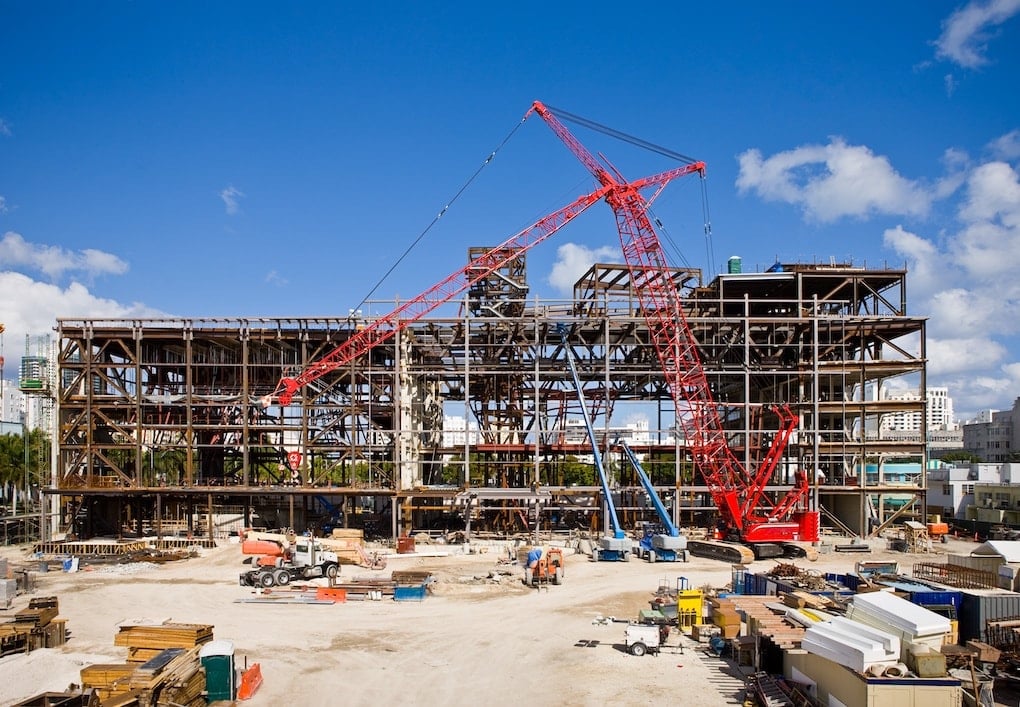 large red crane carrying metal beams; pre-engineered metal buildings average cost