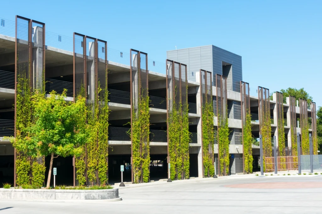 multi level commercial parking garage with green plants growing up the side