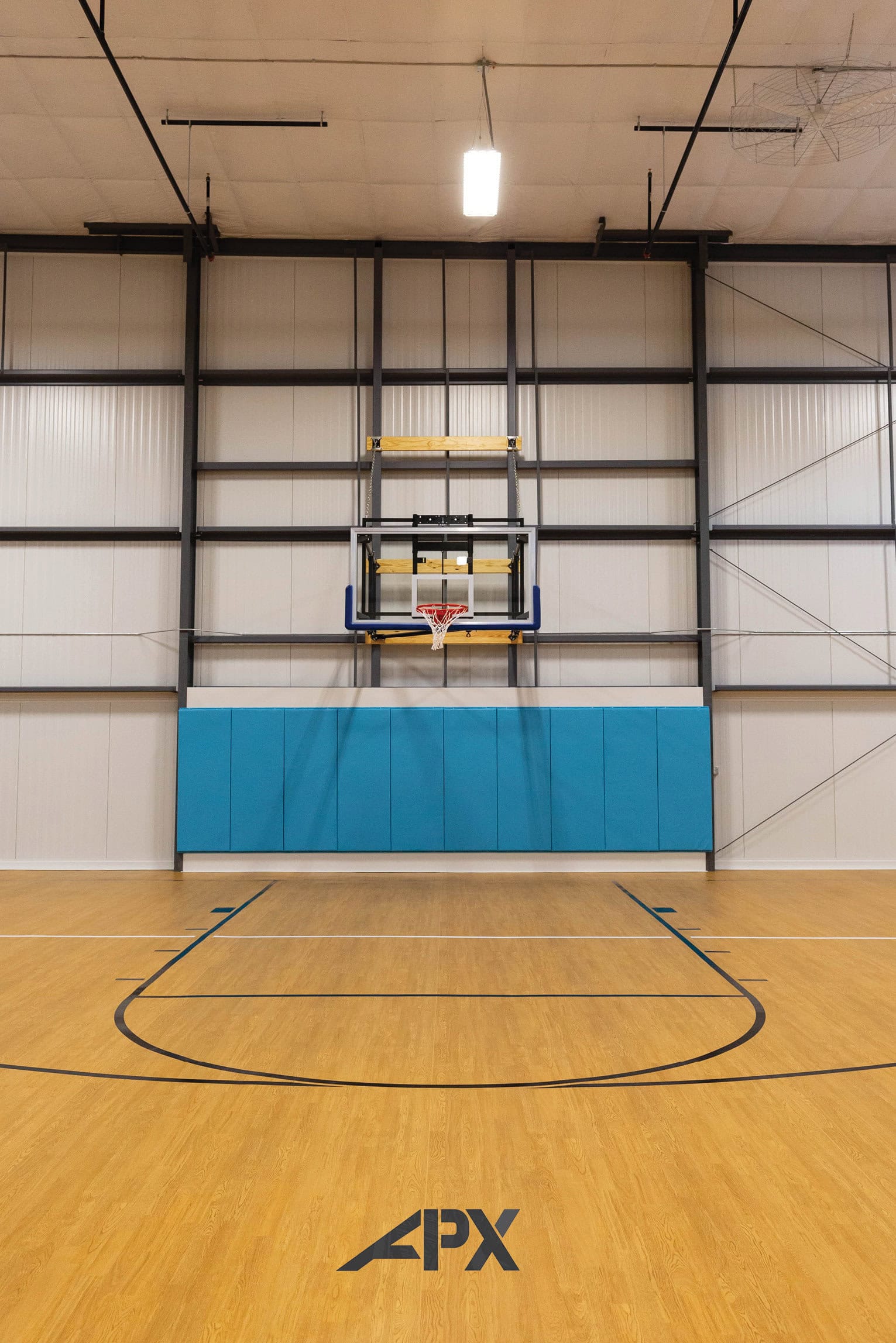 A spacious gym with a variety of modern workout equipment, including basketball hoop, and kids actives. The room has large windows letting in natural light, and a few people are engaged in different exercises, creating an energetic and motivating atmosphere.