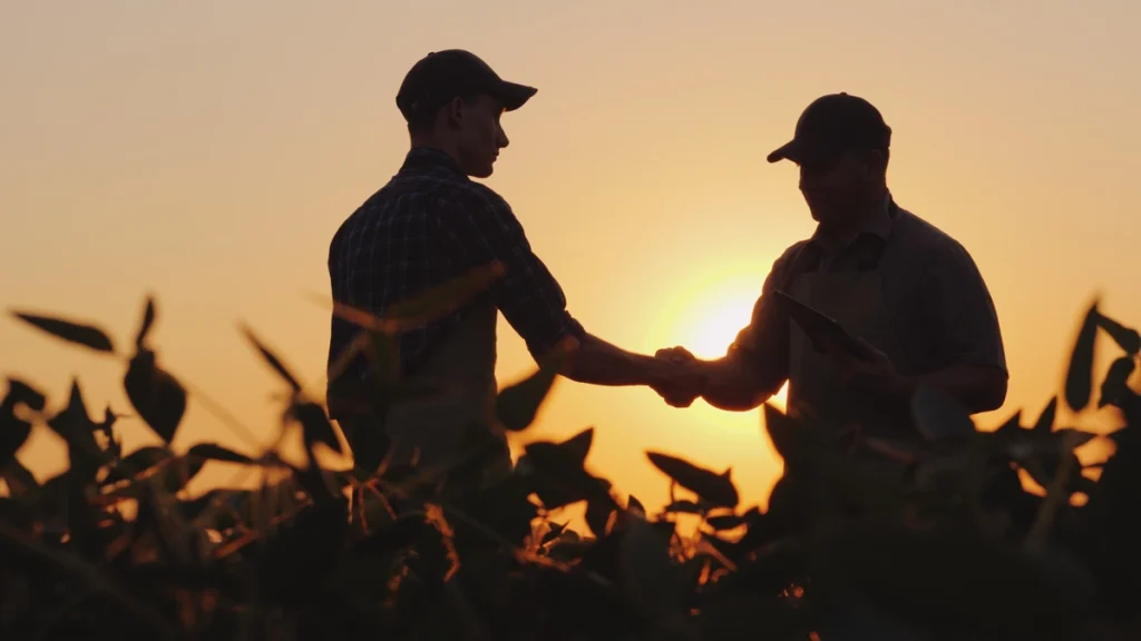 why is agriculture important-two men shaking hands while standing in a crop field