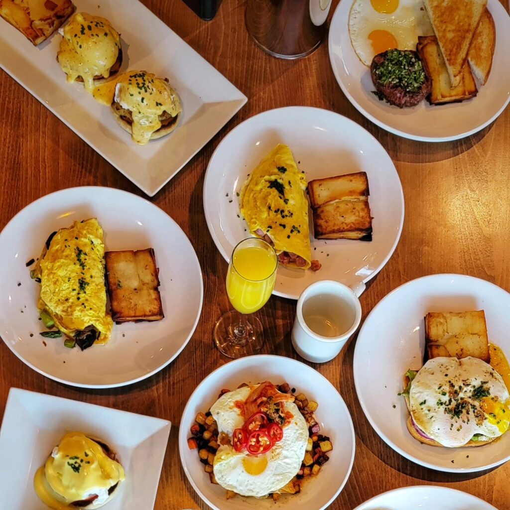 A delicious brunch spread featuring omelets, eggs Benedict, crispy potatoes, toast, and a mimosa, breakfast done right!