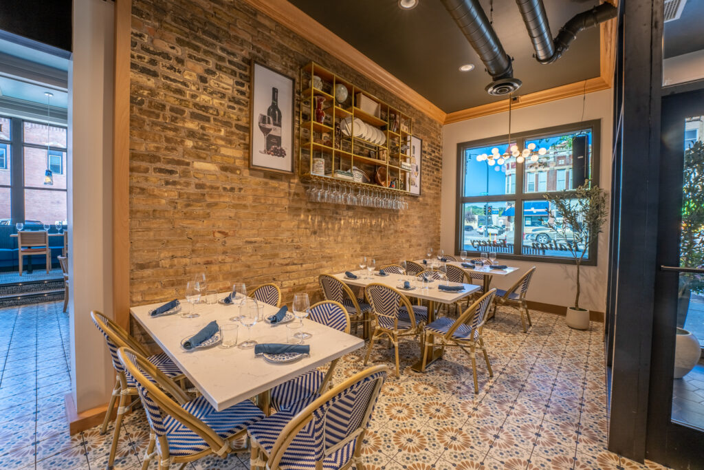 Modern restaurant interior with brick walls, elegant lighting, and cozy dining setup.